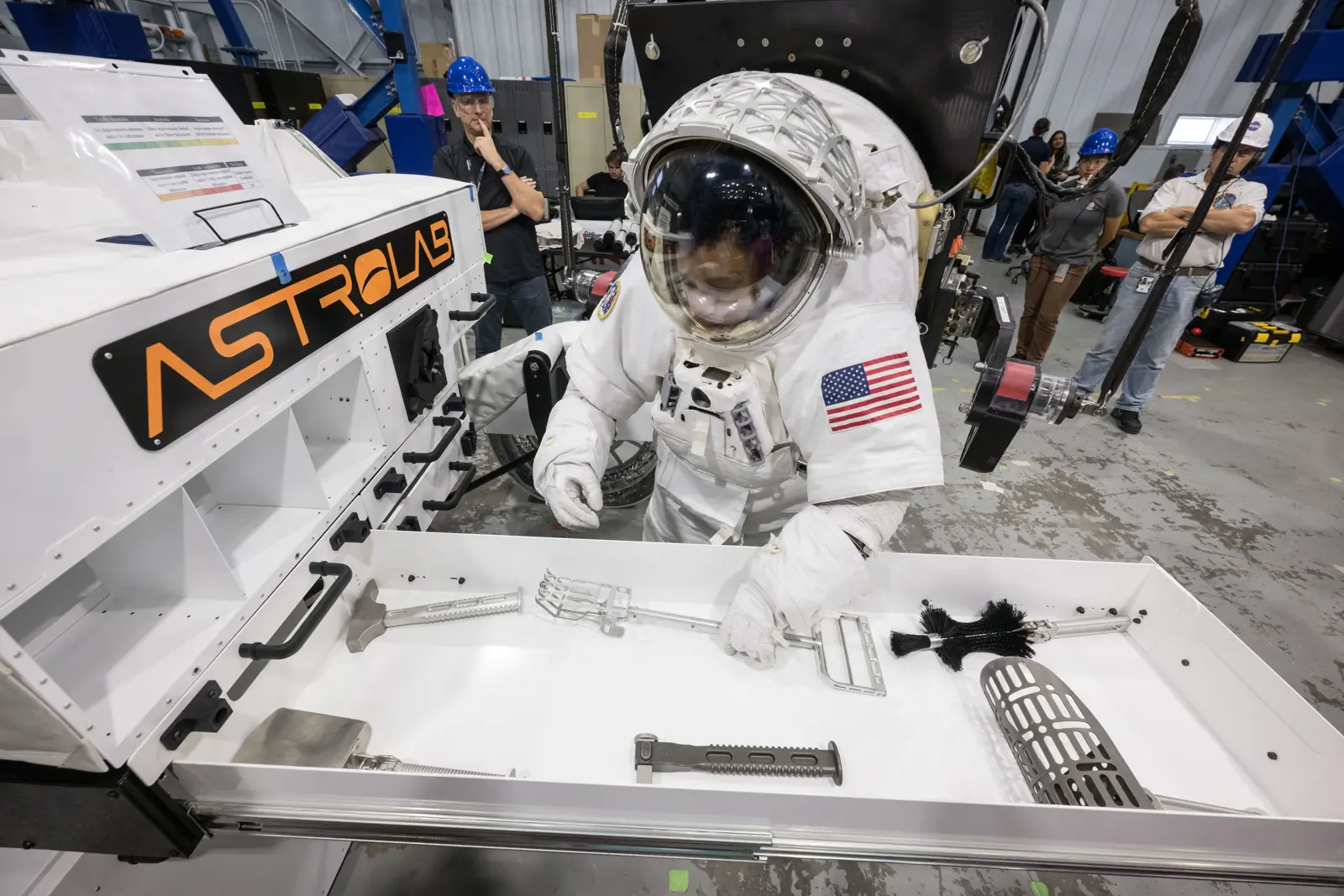 NASA astronaut Jessica Watkins retrieves a lunar geology tool from Astrolab's FLEX lunar terrain vehicle during testing at Johnson Space Center.